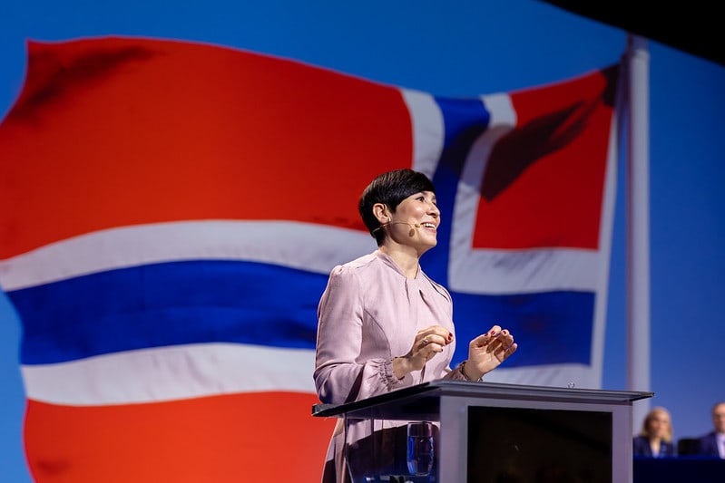 Ine Eriksen Søreide avbildet på scenen på Høyres landsmøte 2023. I bakgrunnen er det norske flagget avbildet med blå himmel.